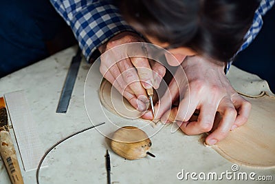 Master artisan luthier working on the creation of a violin. painstaking detailed work on wood. Stock Photo