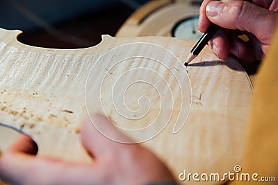 Master artisan luthier working on the creation of a violin. painstaking detailed work on wood. Stock Photo