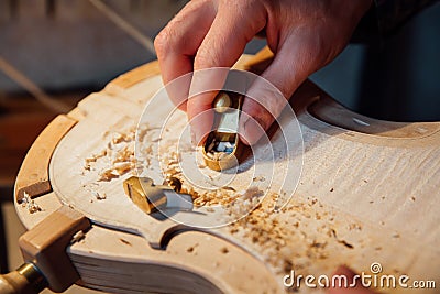 Master artisan luthier working on the creation of a violin. painstaking detailed work on wood. Stock Photo