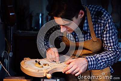 Master artisan luthier working on the creation of a violin. painstaking detailed work on wood. Stock Photo