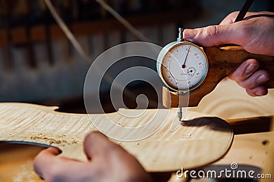 Master artisan luthier working on the creation of a violin. painstaking detailed work on wood. Stock Photo