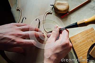 Master artisan luthier working on the creation of a violin. painstaking detailed work on wood. Stock Photo