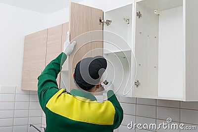Master in the assembly of kitchen furniture, eliminates the guarantee of incorrect operation of door hinges Stock Photo