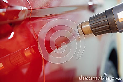 Master auto mechanic heats metal with hairdryer to remove and level out dents and defects on car body on service station Stock Photo