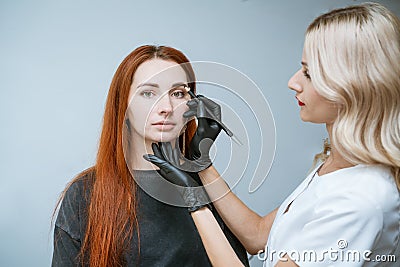 Master beautician makes markup of eyebrow tattooing, women before applying Stock Photo