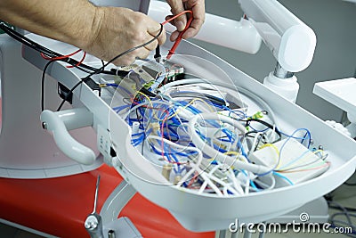 The master checks the electrical circuit in the faulty dental chair with a tester device. Repair of medical equipment Stock Photo