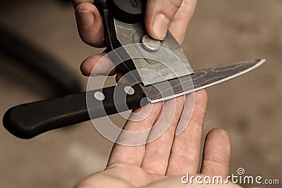 The master checks the sharpening of a knife from Damascus steel Stock Photo