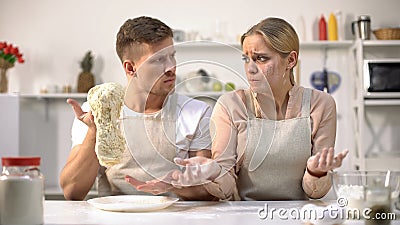 Master chef stretching raw dough, dissatisfied with work of new cook, profession Stock Photo