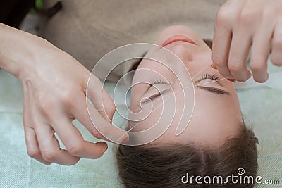 Master corrects makeup gives shape and thread plucks eyebrows in a beauty salon. Stock Photo