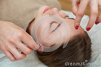 Master corrects makeup gives shape and thread plucks eyebrows Stock Photo