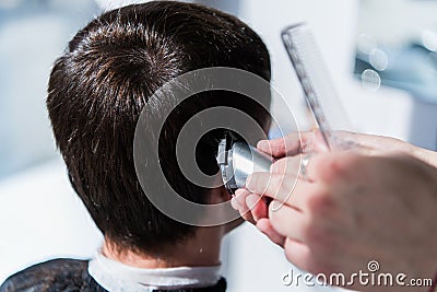 Master cuts hair of men in the barbershop, hairdresser makes hairstyle for a young man Stock Photo