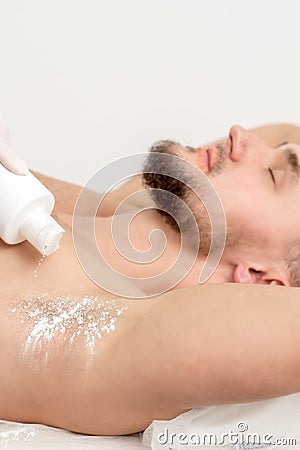 Master depilation pouring talcum powder on armpit Stock Photo