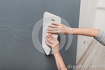 Master hands using spatula smooth out the bubbles and creases on the whimsical monochrome blue wallpaper on the wall Stock Photo