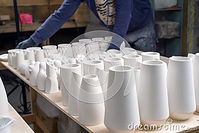 The master lays out Finished plaster products on the table: vases, figurines, bowls. Making and casting in the workshop decorative Stock Photo