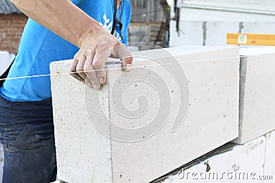 The master lays a wall of blocks. Builder builds a concrete wall made of cement blocks on the construction site of a residential Stock Photo