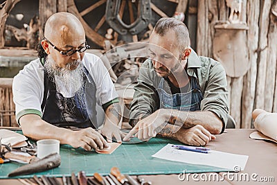 master of leather tailor teaching and training young man for making handcraft leather pouch Stock Photo