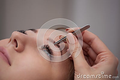 Master makeup corrects, and gives shape to pull out with forceps previously painted with henna eyebrows in a beauty salon Stock Photo