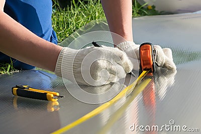 Master measures tape measure the size of polycarbonate for the greenhouse Stock Photo