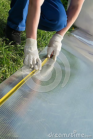 Master measures tape measure the size of a polycarbonate sheet for a greenhouse Stock Photo