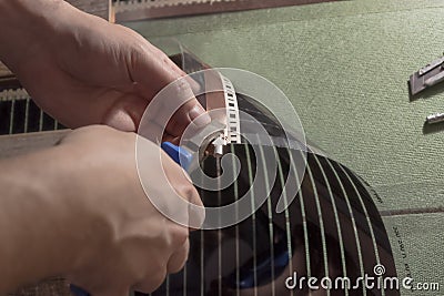 The master with pliers fixes the clamp into a copper strip on a film heated floor, for connecting wires. The edge of the film is Stock Photo