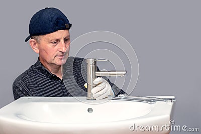 The master plumber screws the faucet to the sink in the bathroom Stock Photo