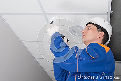 A master in a protective helmet for the maintenance of fire alarms, conducts an inspection in the residential sector Stock Photo