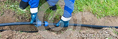 Master puts a black pipe in the ground, long Stock Photo