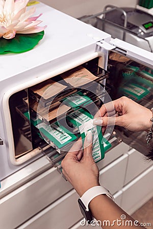 The master puts the manicure tools into the sterilizer. Sterilization of instruments in a beauty salon. Sterilization. Equipment Editorial Stock Photo