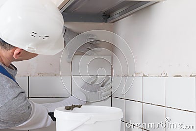 The master puts the white tile in a new row on the wall, gluing it on the mortar Stock Photo