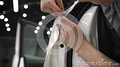 The master sticks a white protective film on the car body. Wrapping a car body with a white protective film. nstallation Stock Photo