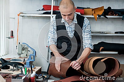 A master in the workshop, carefully examining the leather rolls Stock Photo