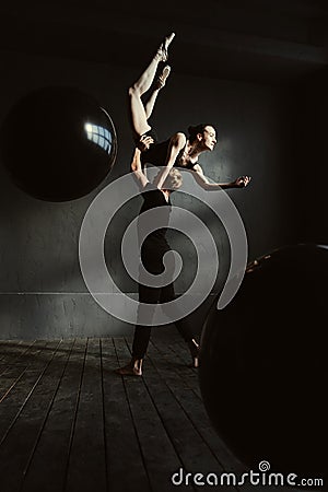 Masterful gymnasts dancing together in the black colored studio Stock Photo