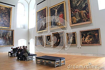 Masterpieces arranged on walls, with simple benches and people admiring, The Louvre,Paris,2016 Editorial Stock Photo