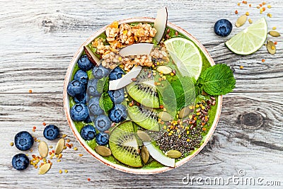 Matcha green tea breakfast superfoods smoothies bowl topped with chia, flax and pumpkin seeds, bee pollen, granola, coconut flakes Stock Photo