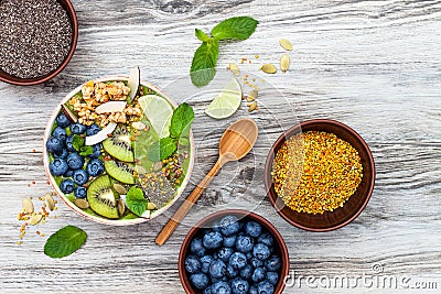 Matcha green tea breakfast superfoods smoothies bowl topped with chia, flax and pumpkin seeds, bee pollen, granola, coconut flakes Stock Photo