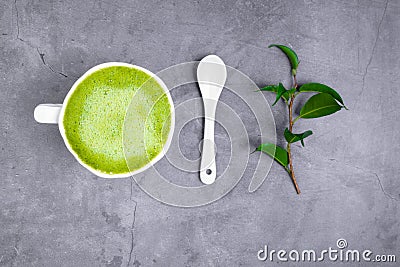 Matcha green tea latte beverage in white ceramic cup with spoon, green leaf Stock Photo
