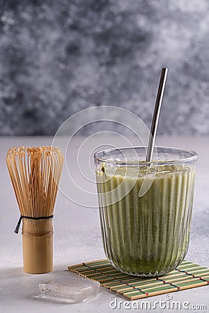 Matcha latte with cream foam in glasses, bamboo whisk tusaku and matcha powder on table Stock Photo