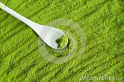 Matcha powder background with small white spoon. Green tea texture close up Stock Photo