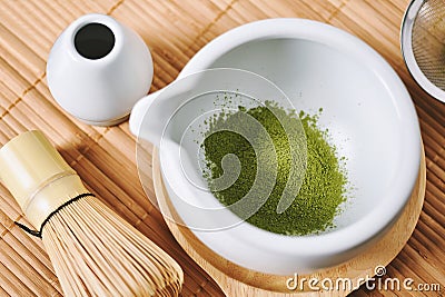 Matcha tea powder in white clay tea bowl, Matcha bamboo whisk and accessories, Green tea making set Stock Photo