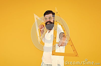 Math genius. Geometry geek holding triangles on yellow background. Geek or nerdy student making angle. Bearded man in Stock Photo