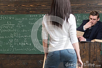 Math professor staring at his young beautiful female student. Turn back girl with nice standing in front of green Stock Photo