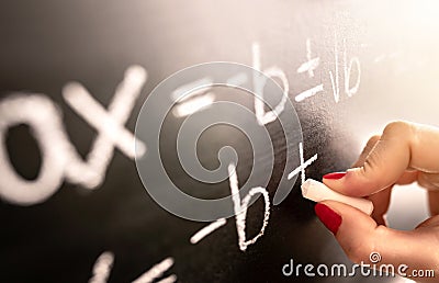 Math teacher writing function, equation or calculation on blackboard in school classroom. Stock Photo