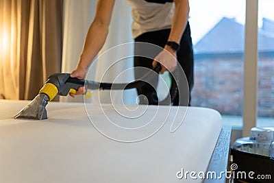 Mattress cleaning process. Man cleans bed from dirt and bacteria. Stock Photo