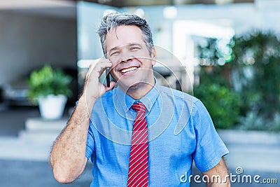 Mature adult businessman with grey hair talking with customer at phone Stock Photo
