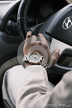 a man driving a car with a gold wrist watch on his wrist Editorial Stock Photo