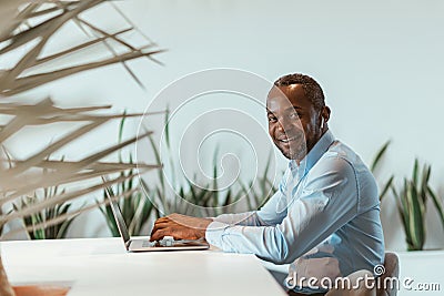 Mature african businessman workingon on laptop while sitting in modern coworking Stock Photo