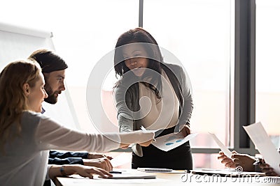 Mature asian female coach giving handout materials during corporate seminar Stock Photo