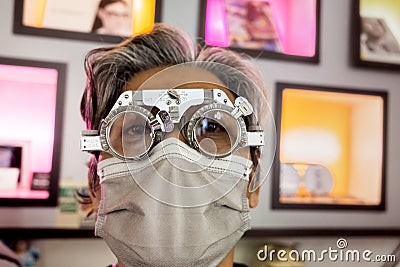 Mature Asian man wearing phoropter for vision correction at eyeglasses store Stock Photo