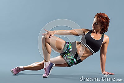 Mature athletic redhead woman doing fitness exercises, gray studio background Stock Photo