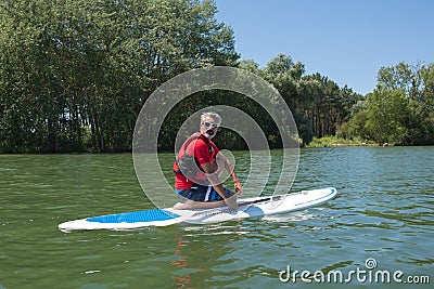 Mature attractive rider contemplating nature sitting on paddle board Stock Photo